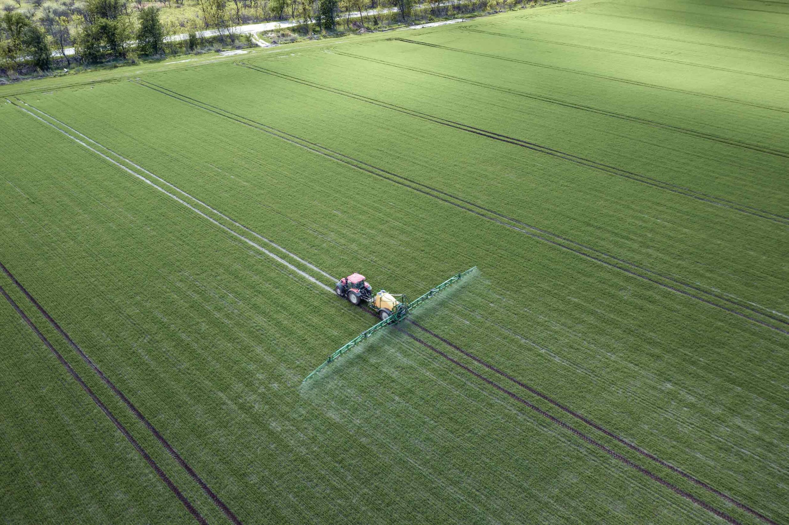 Ein Traktor spritzt Pflanzenschutzmittel auf einem Feld.